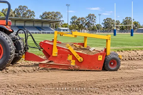 Red scraper preparing a rugby ground — application concept